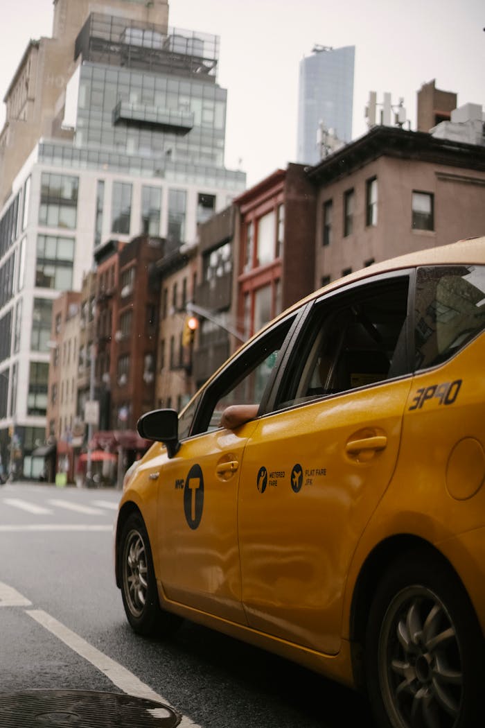 services-02 Yellow taxi car ridding on carriageway on street with buildings in town in daytime